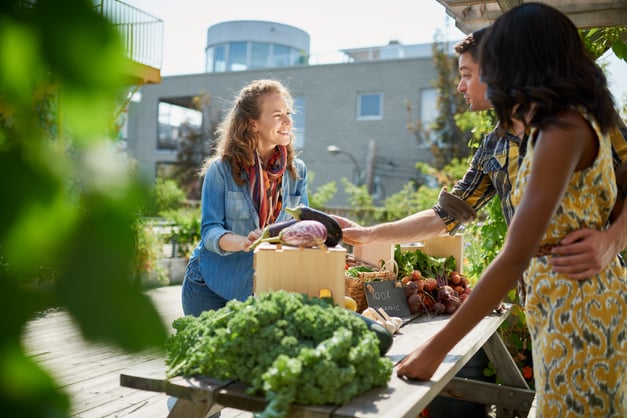 Woman getting vegetables from a farmers market stand