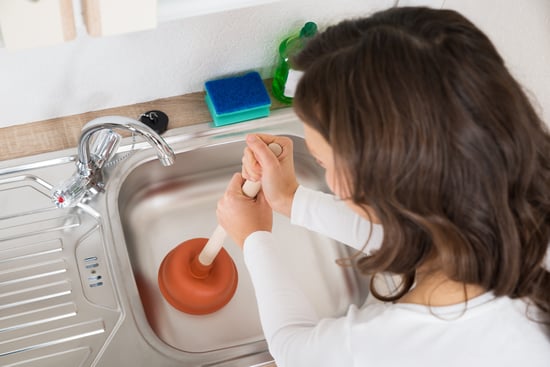 woman unclogs kitchen drain