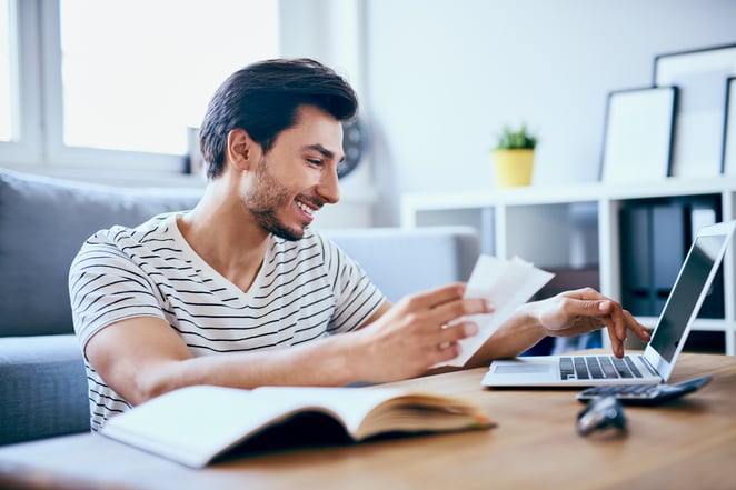 happy man paying bills in his living room