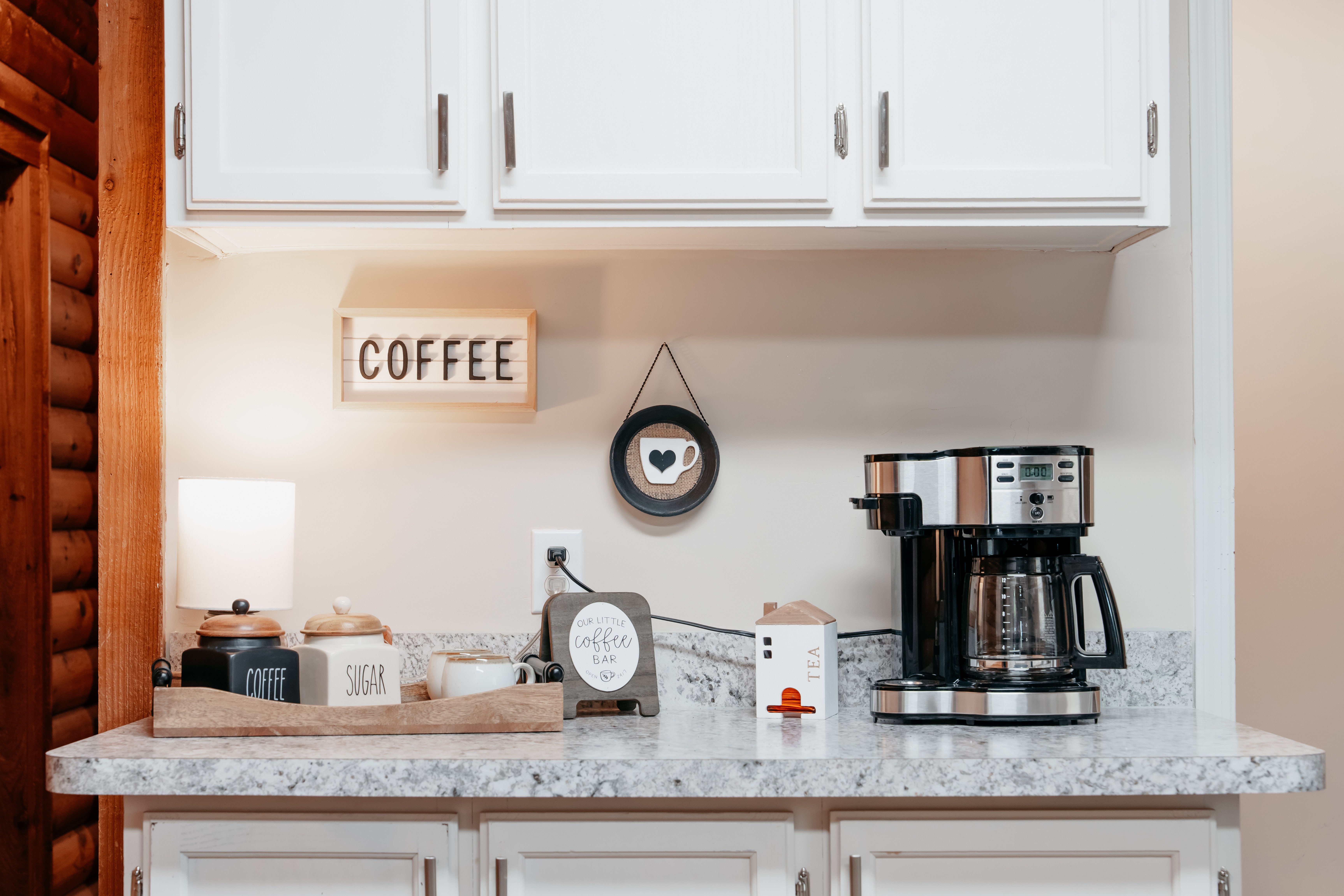At-home coffee bar with coffee maker, decorations, and a place for coffee and sugar.