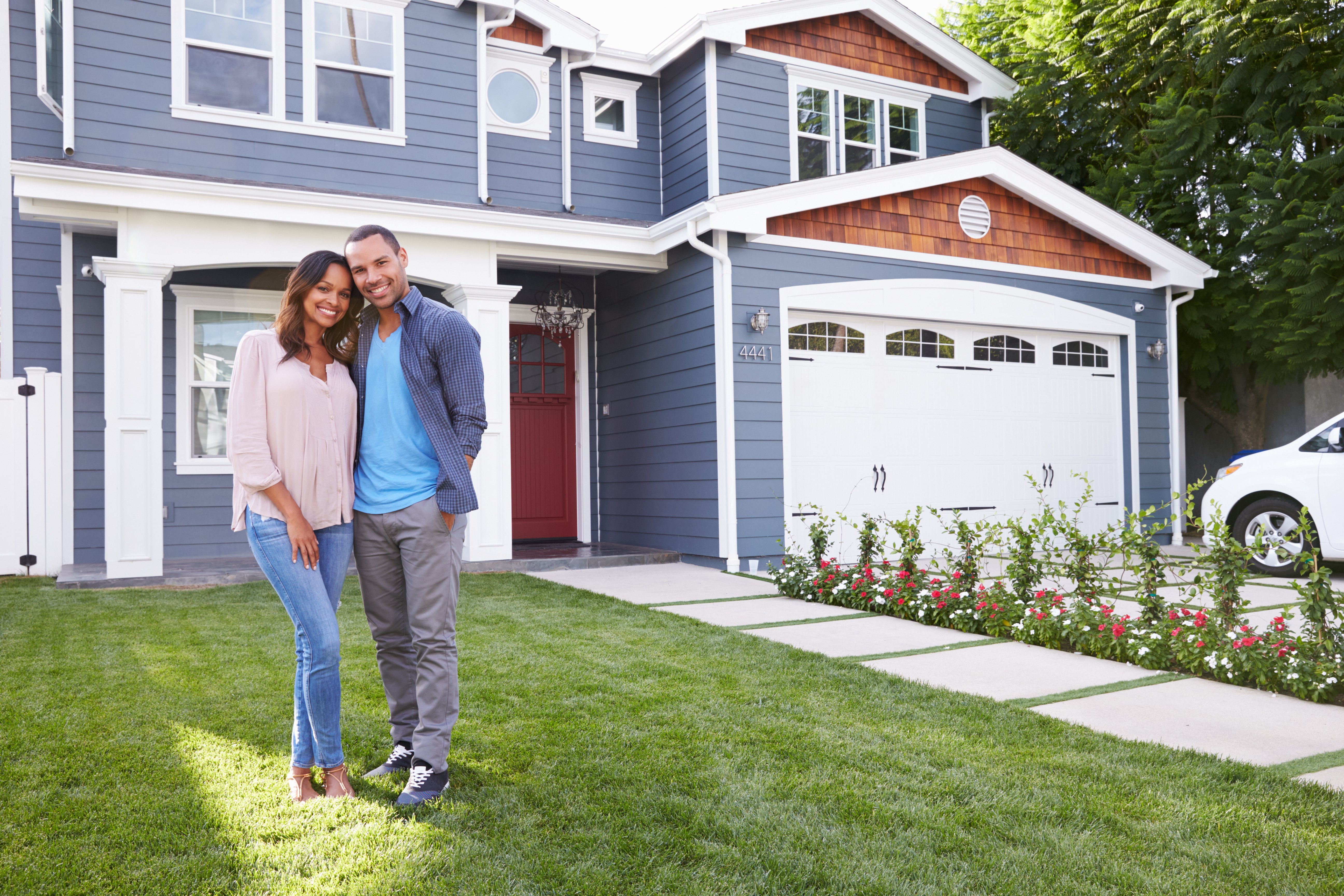 A couple smiling in front of a house 