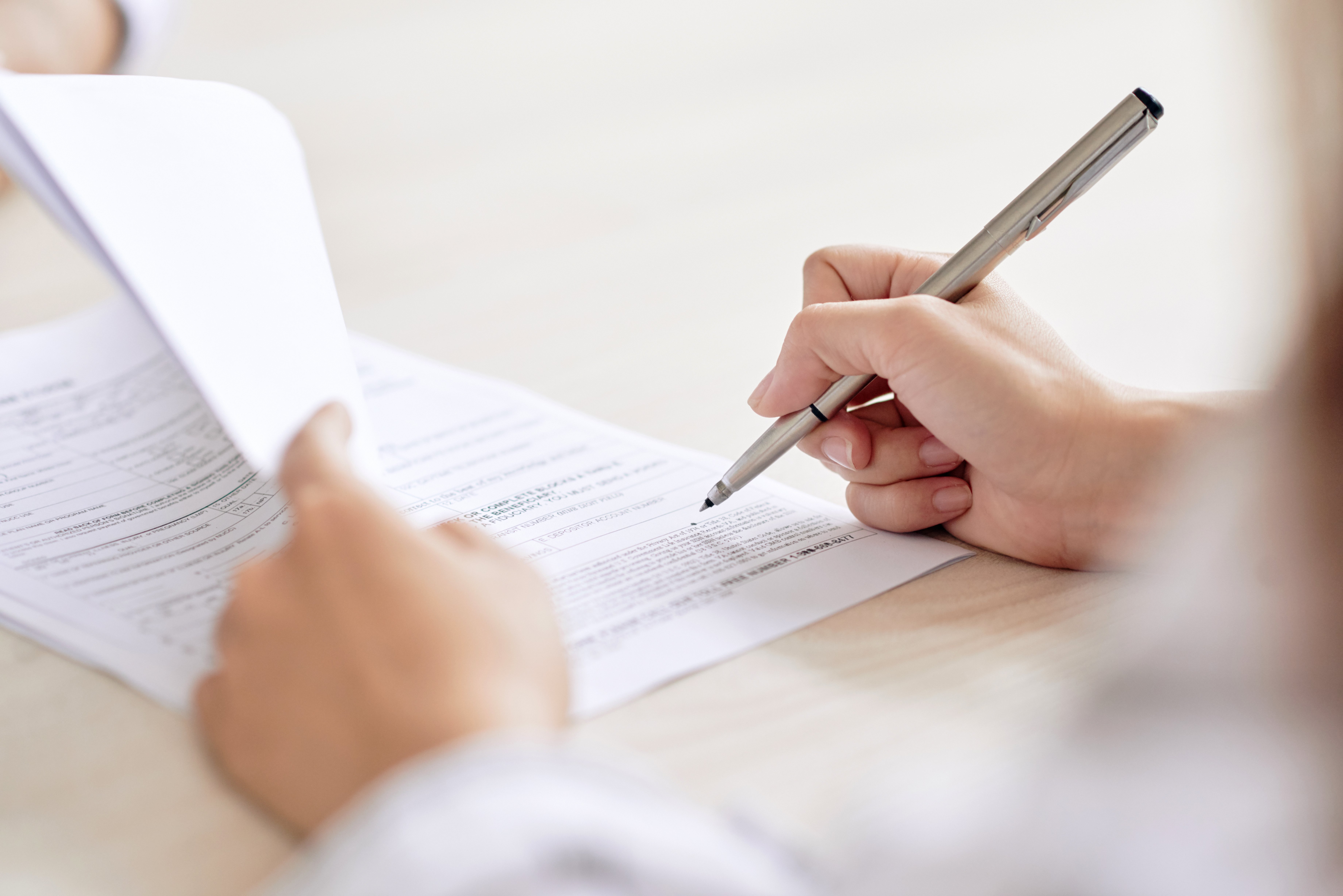 person  holds packet of paper with a pen in their hand