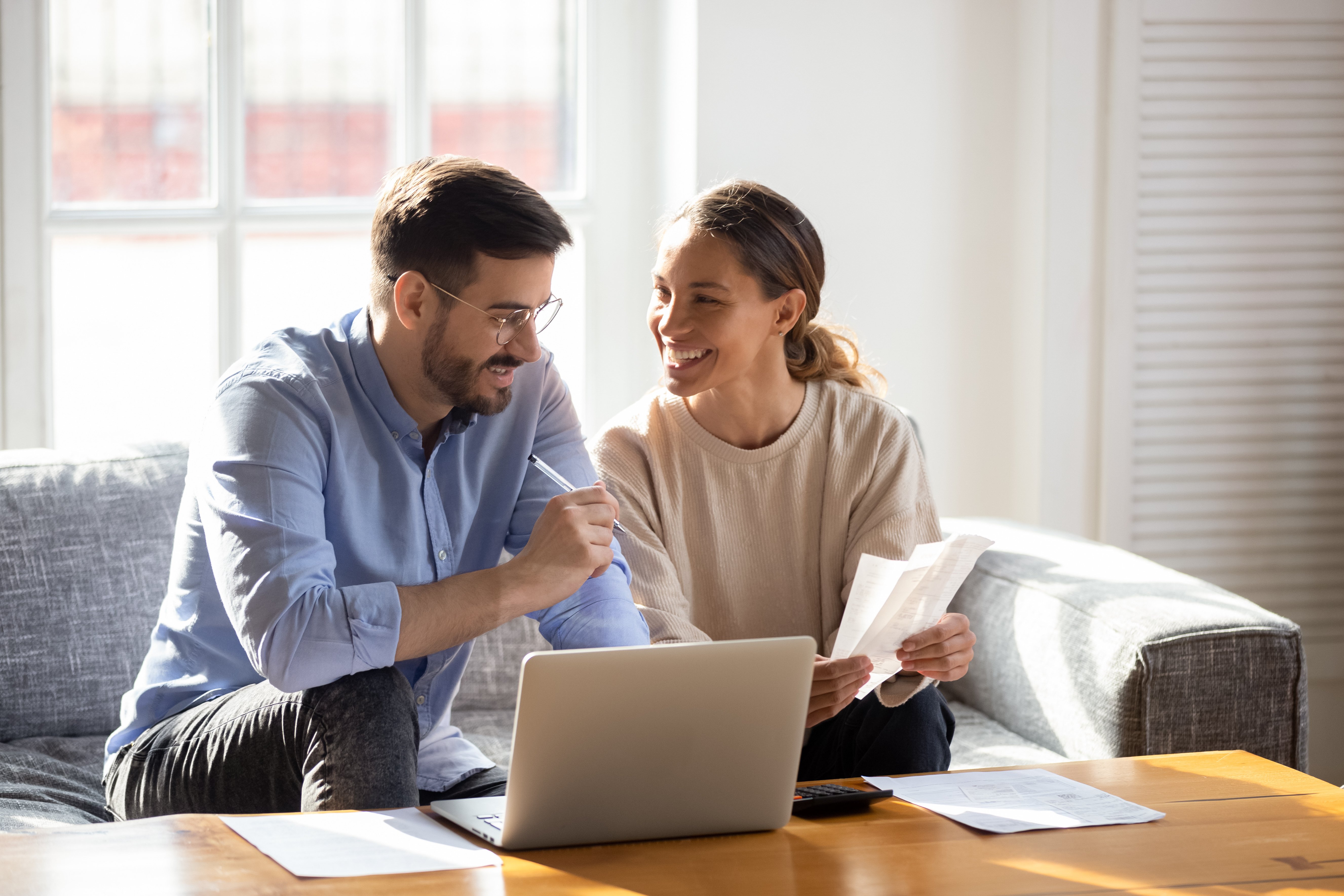 A happy young couple is paying bills online.