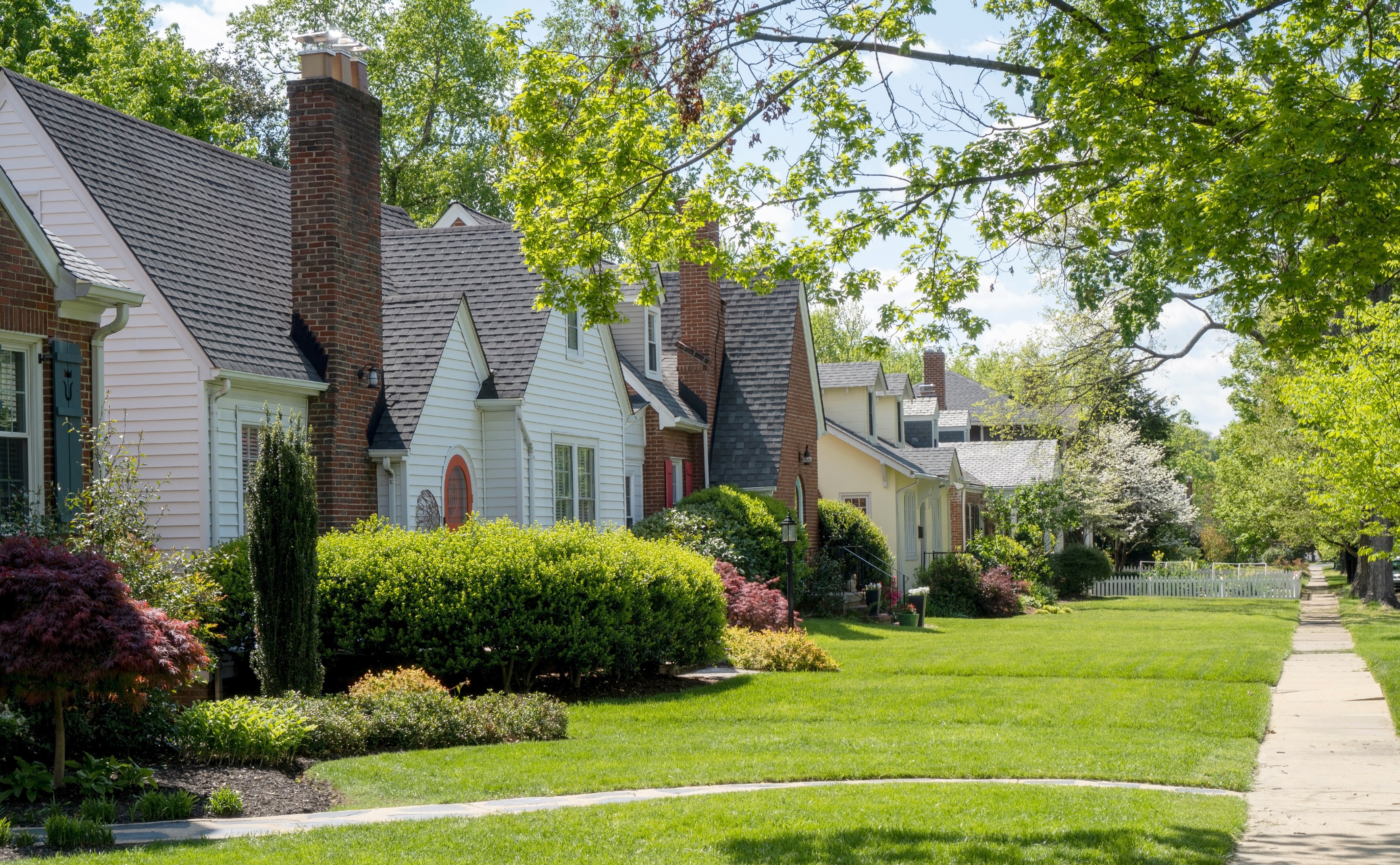 Row of houses in neighborhood. Sidewalk and front yards visible. 