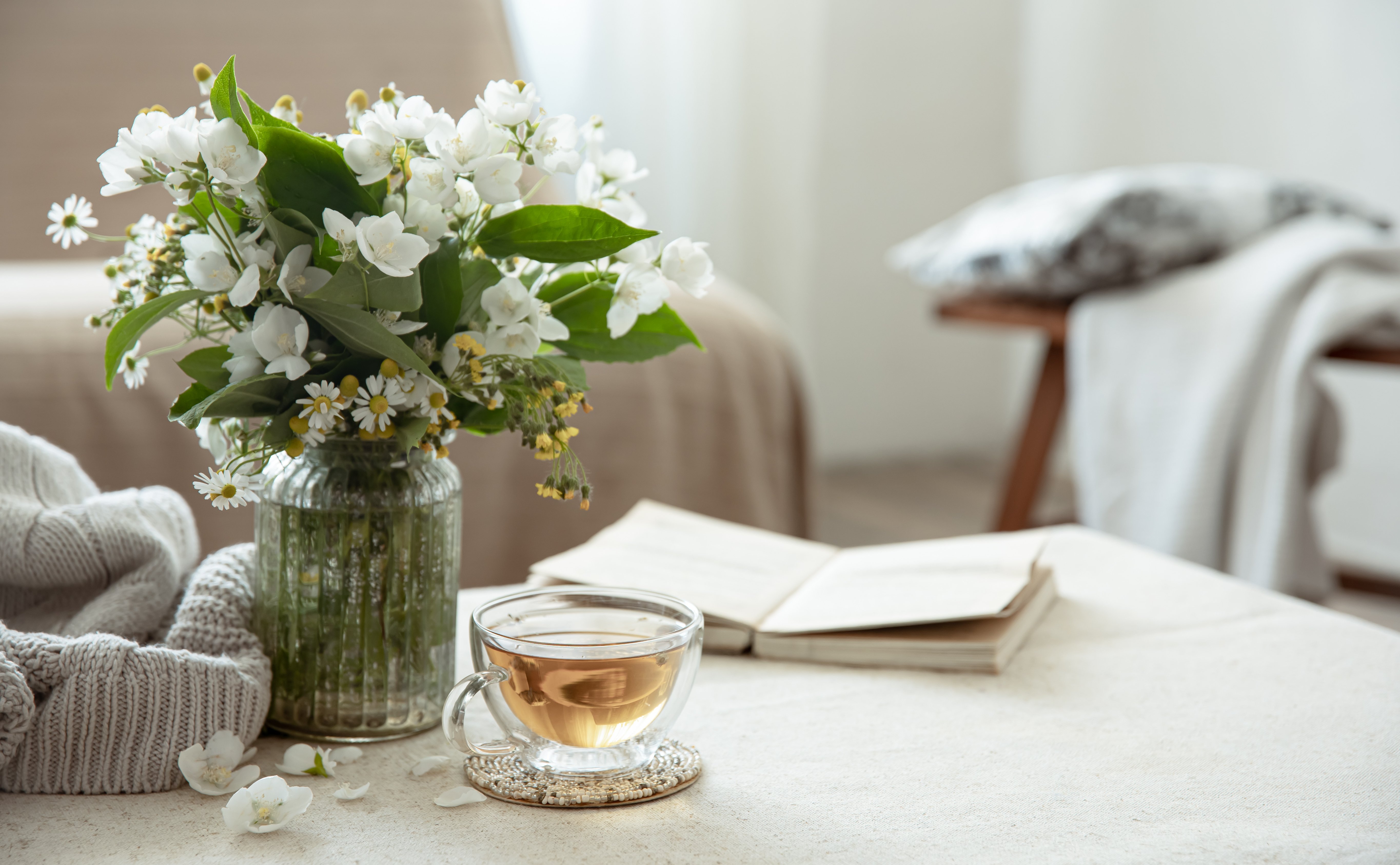 Cozy home composition with a cup of tea, a book and white flowers.