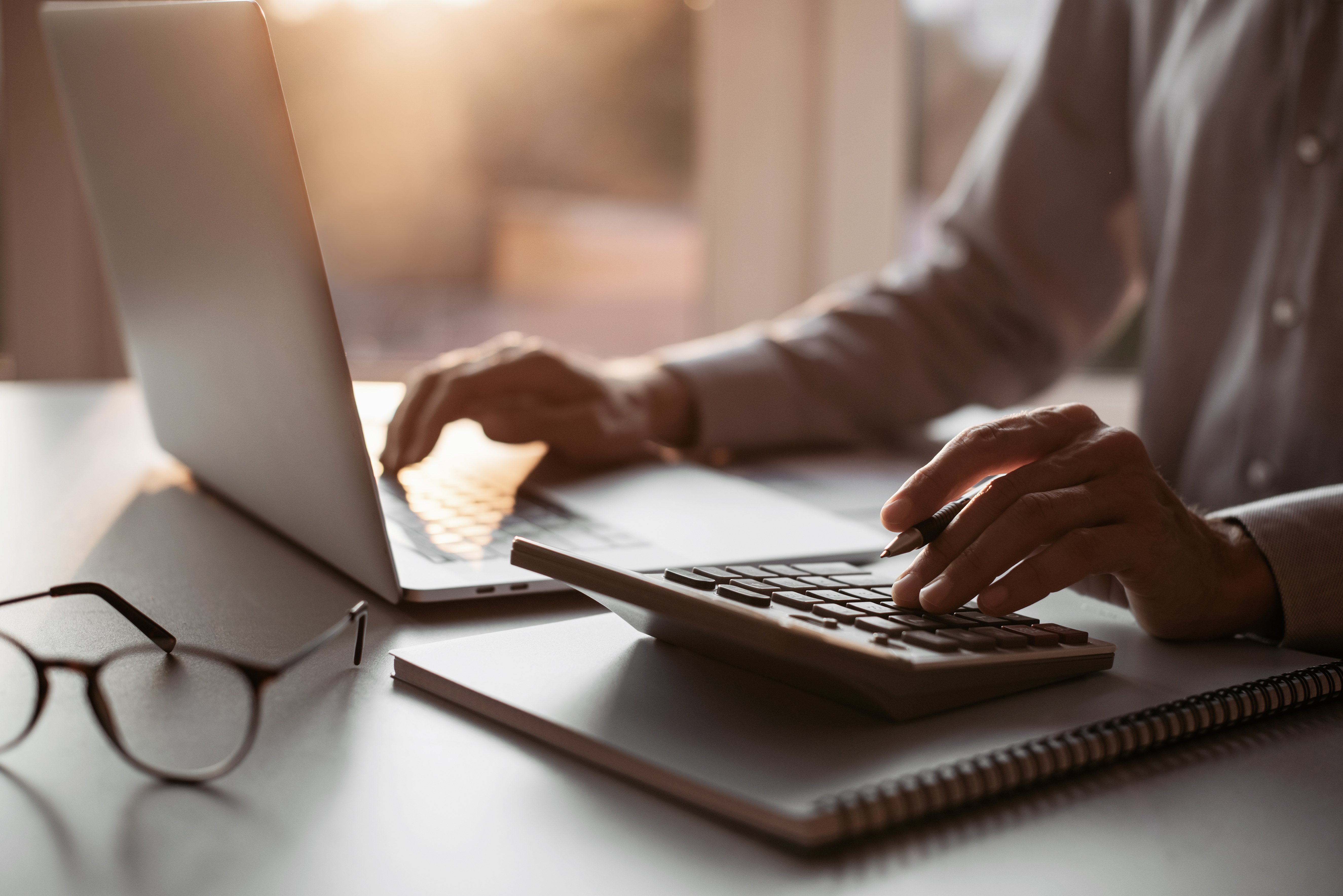 Man accountant using calculator and laptop computer in office