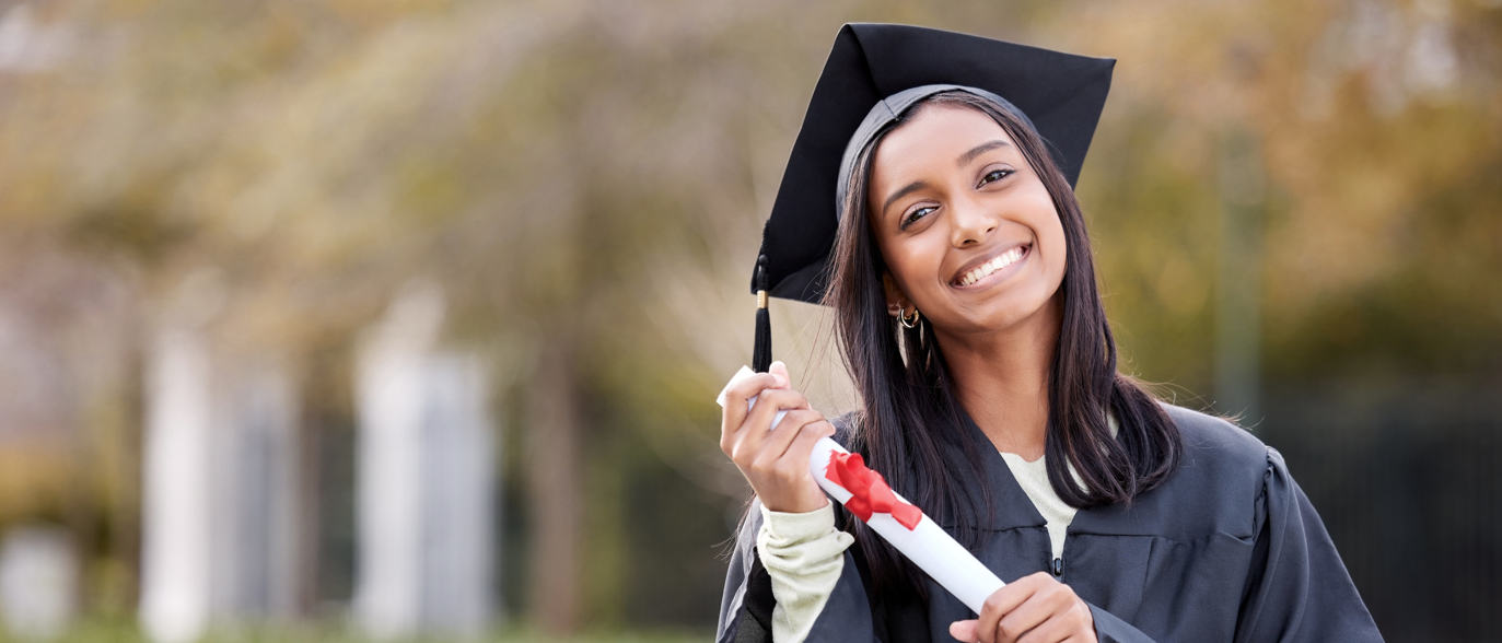Portrait of college student and with certificate on her graduation day outside.